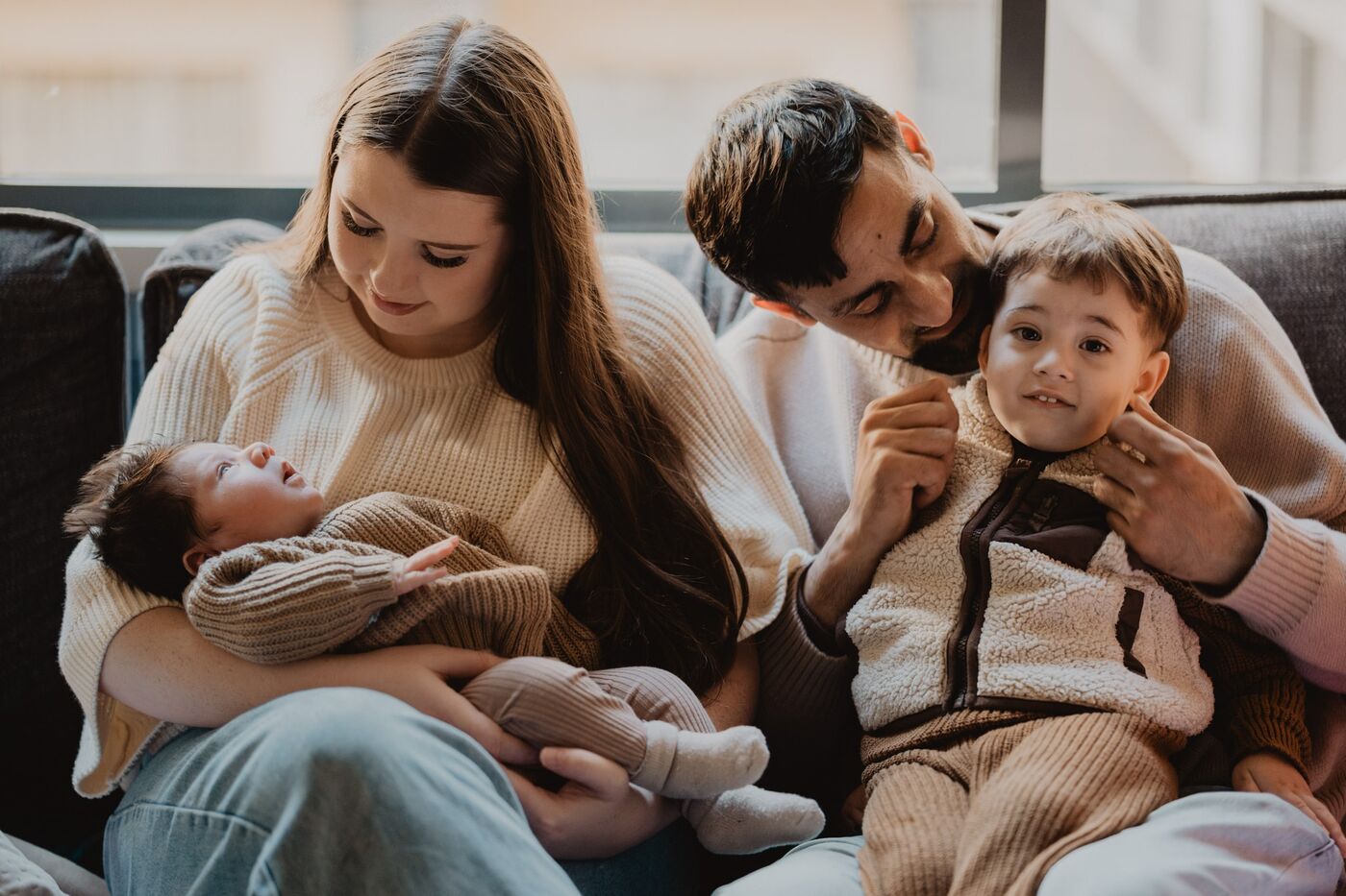 A family on a couch with their newborn and toddler